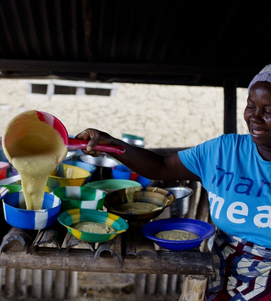 Mary's Meals volunteer pouring porridge into smaller bowls